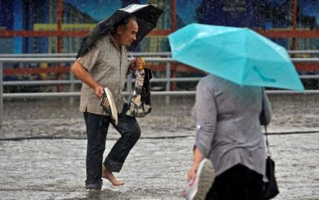 _doshch_zliva_kalyuzha_cholovik_znyav_krosivki_stoyit_u_vodi_parasoli_teplo_z_22.05.26