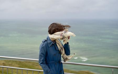 _viter_zhinka_sine_palto_shal_zakrivae_oblichchya_more_zalizniy_parkan_gettyimages_221263_24.04.26