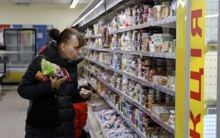 _zhinka_bilya_stelazhu_z_molochkoyu_holodno_puhovik_pokupki_v_rukah_i_sir_12.03.26